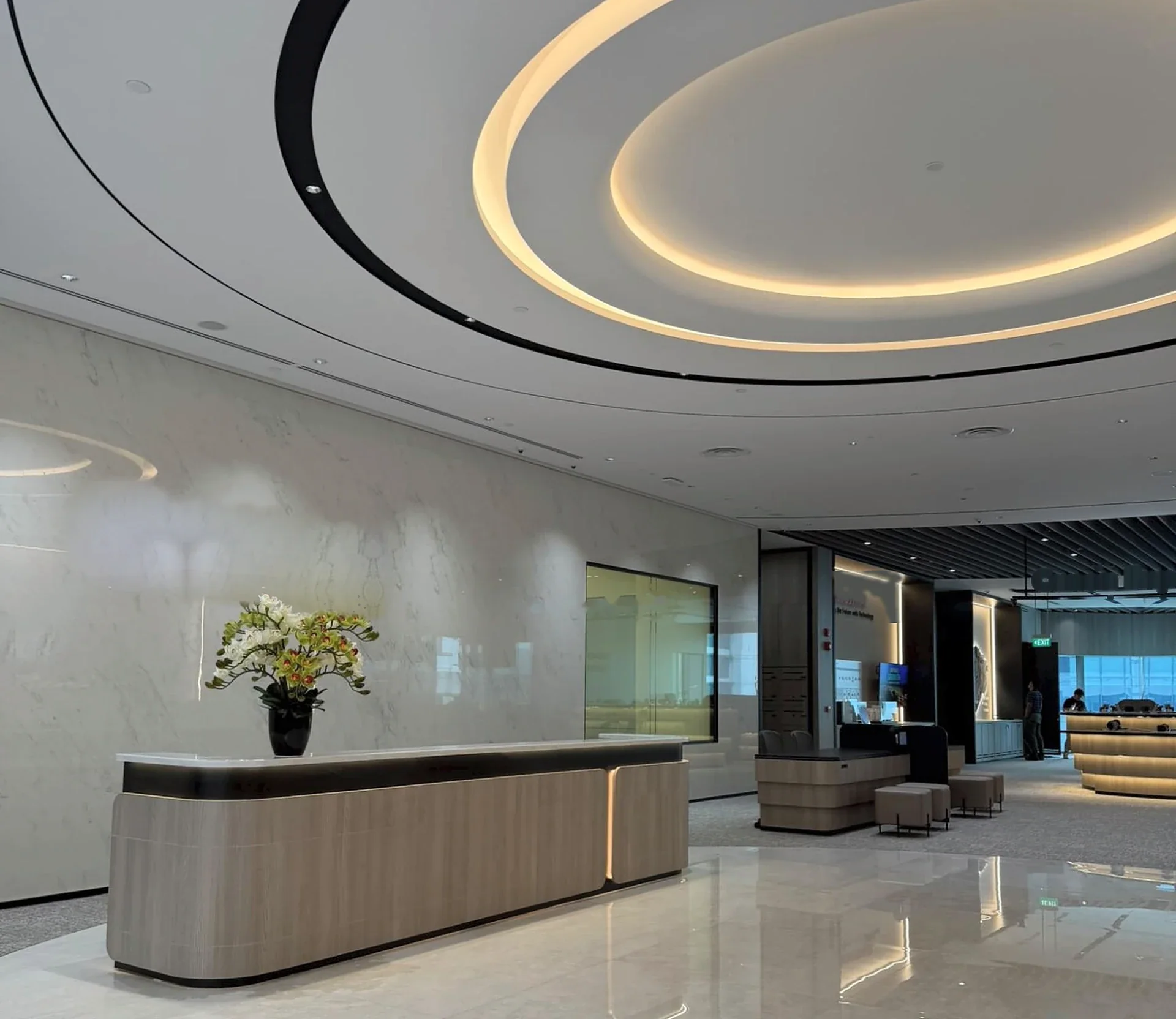 A finished office reception with an oval cove of warm LED light above the counter, wired and lit by BSH