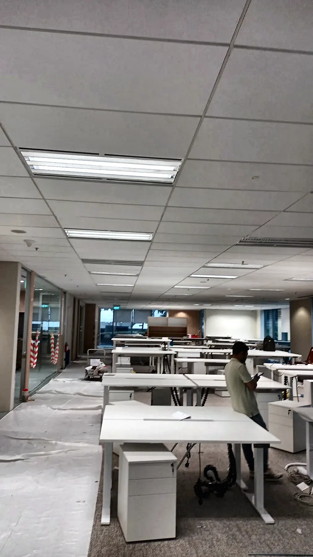 Open-plan office with a linear ceiling luminaire above newly installed desking.