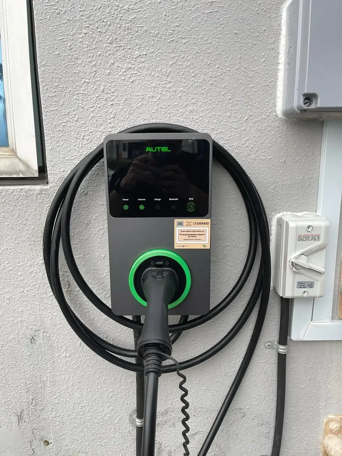 Autel 7 kW EV charger with illuminated status ring, isolator and surface conduit alongside.