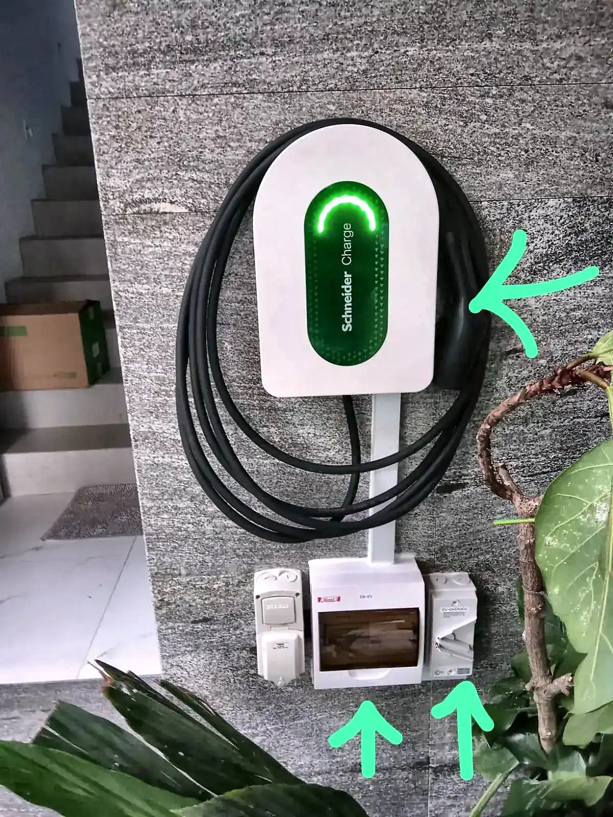 Schneider Charge 7 kW wallbox with arrows marking the charger and the isolators mounted beneath it.