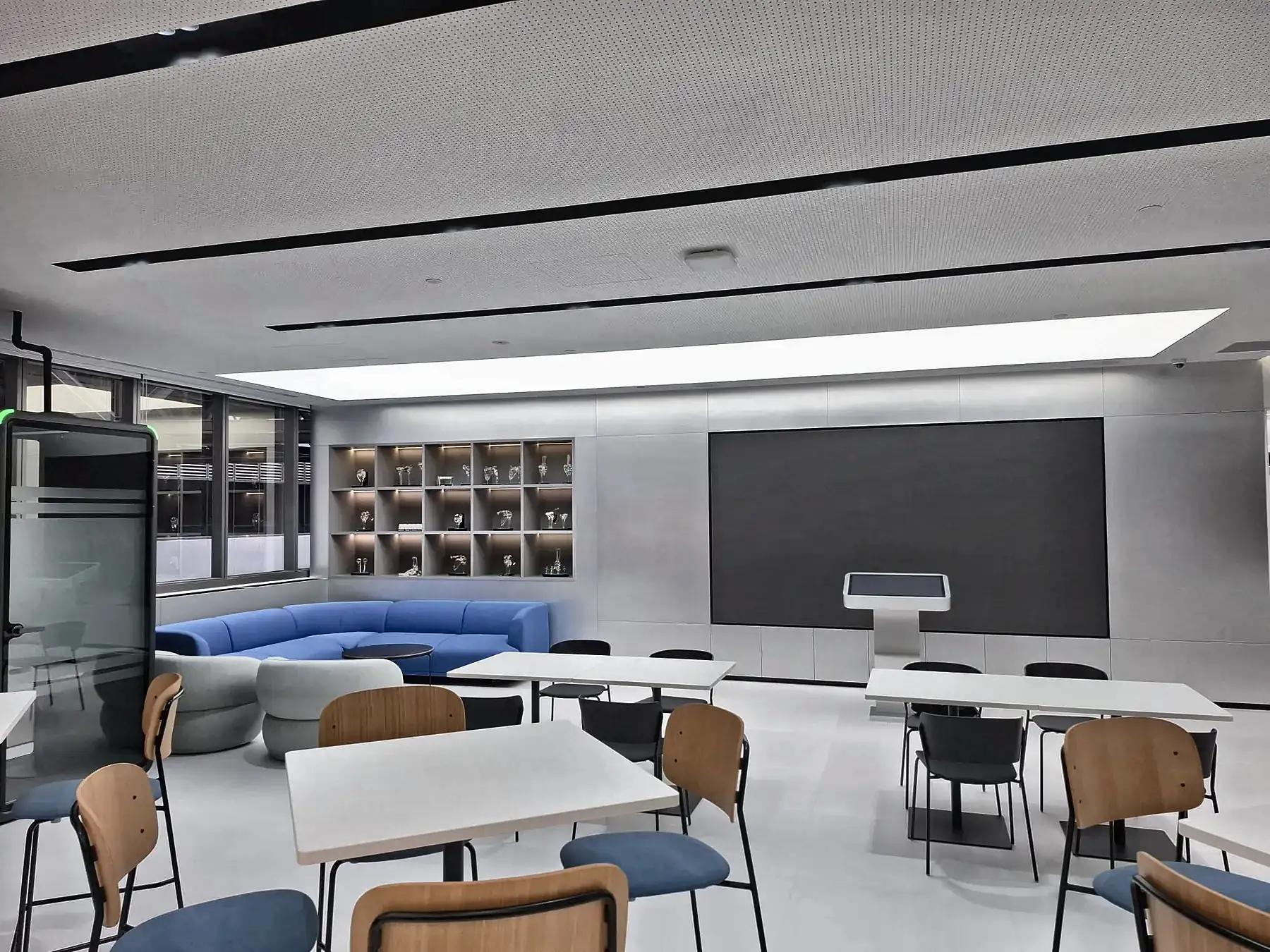 Completed training room with recessed cove lighting, ceiling light panel and wall display screen.