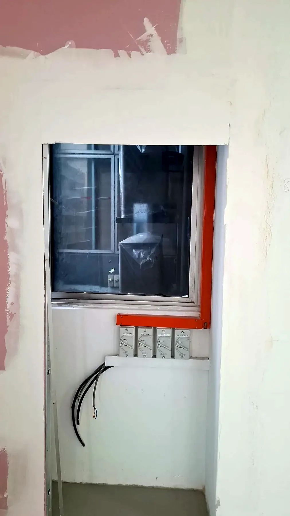 Wall riser opening with conduits and cabling passing through between floors.