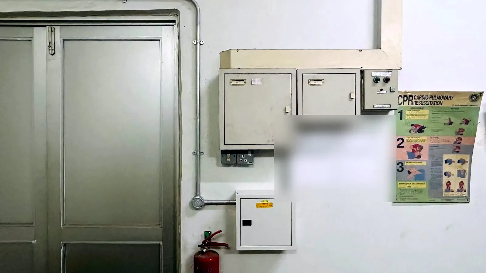 Switchroom wall with metal distribution board enclosures, safety signage and posted licence notices.