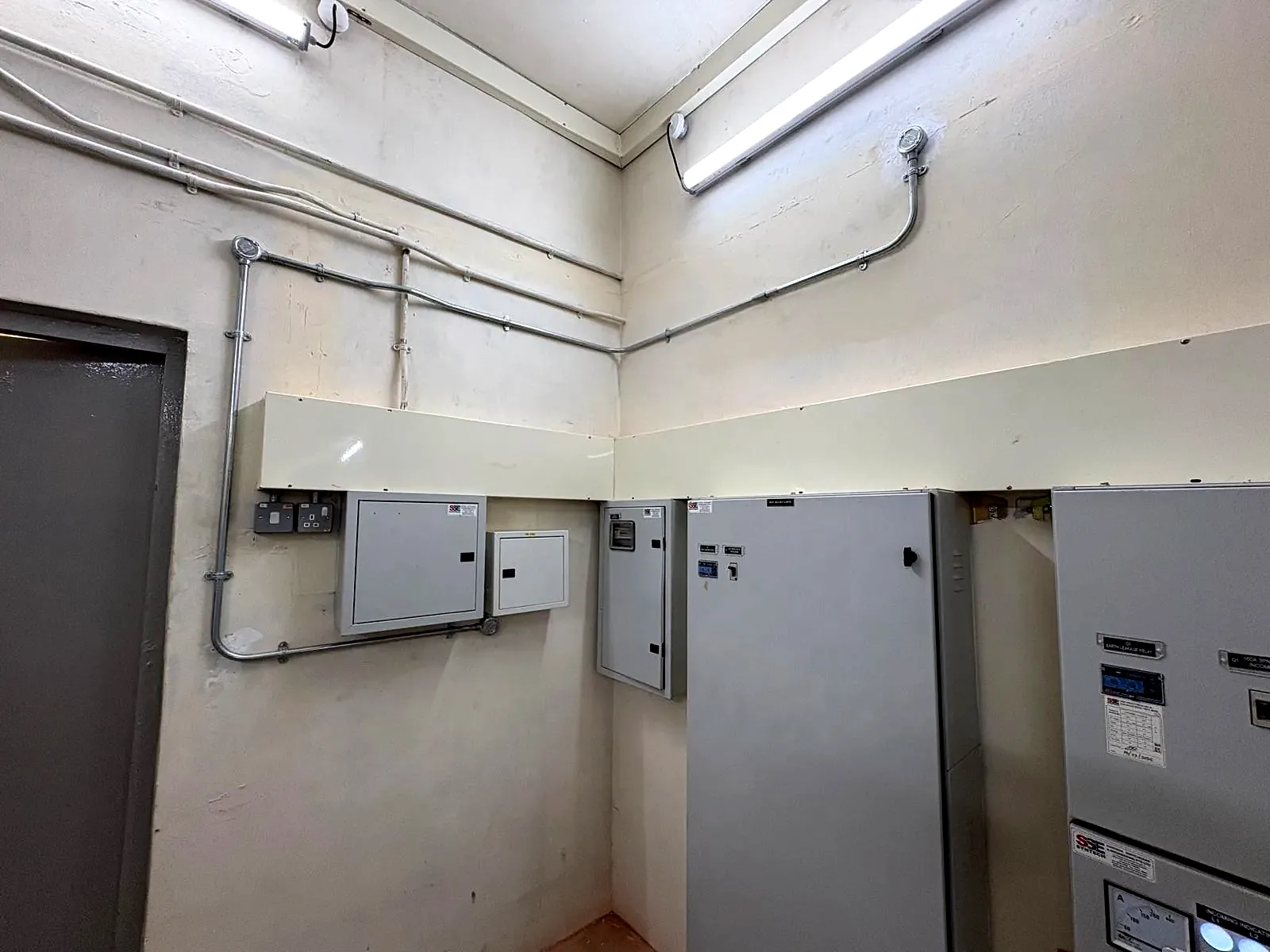 Switchroom with surface conduit runs, wall-mounted distribution boards and batten lighting.