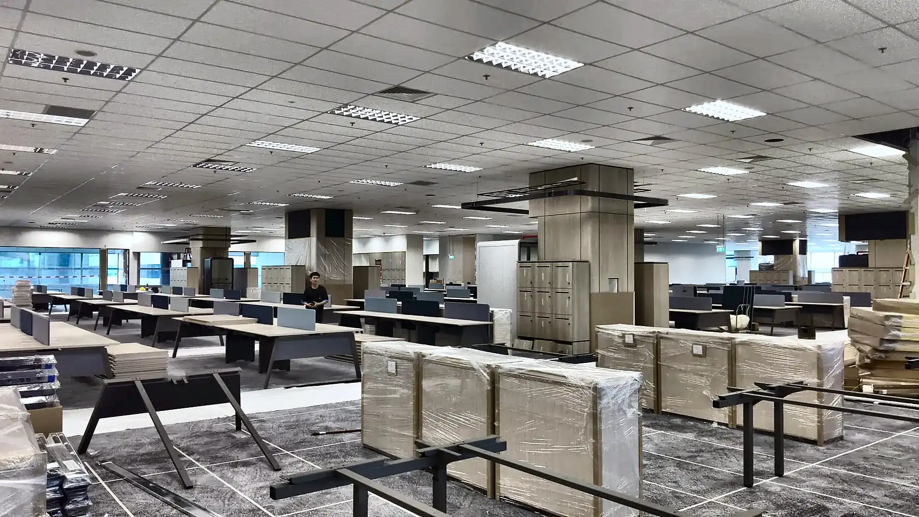 Office floorplate with ceiling lighting running while furniture is installed ahead of handover.