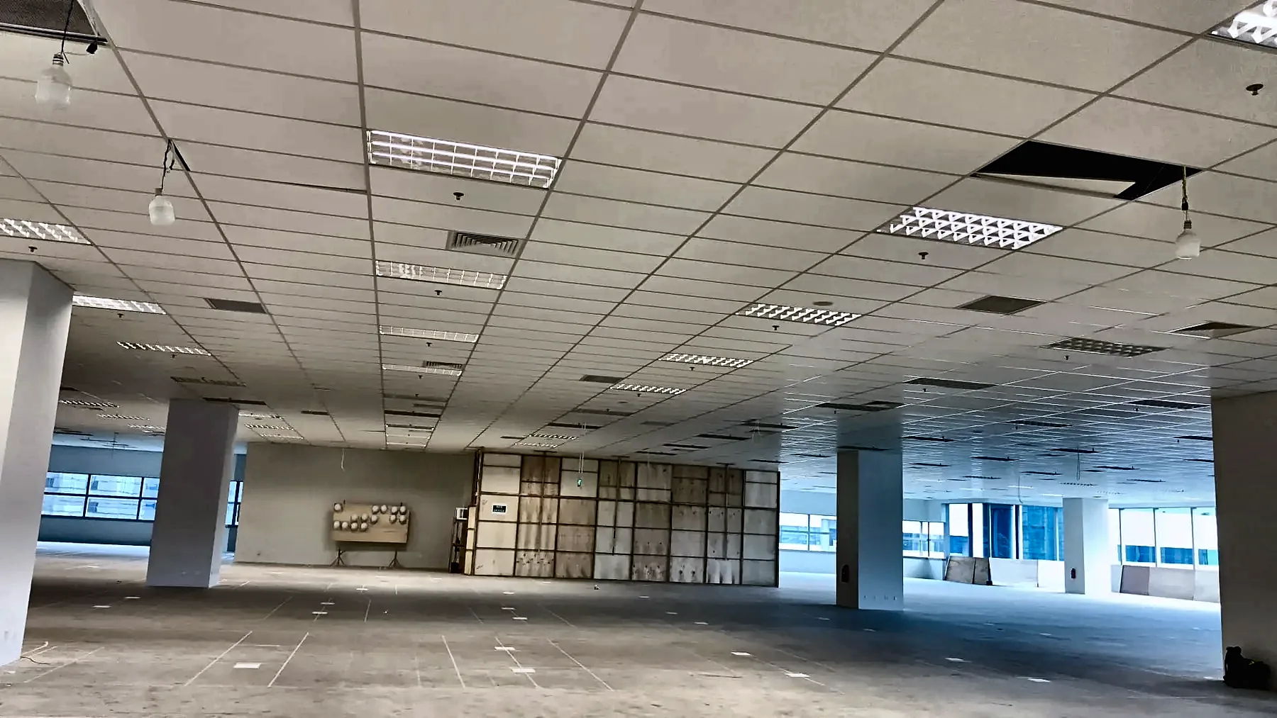 Open-plan floorplate with recessed luminaires installed into a suspended ceiling grid.